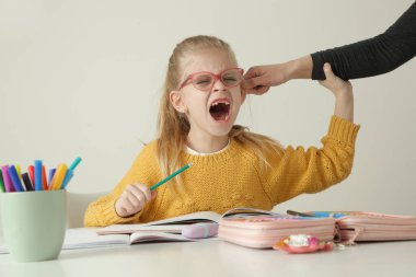 İtaatsiz küçük kız ödevlerini yaparken kulaklarından tutup cezalandırılıyor.