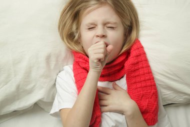 7 yaşında küçük bir kız çocuğu yatakta uzanıyor ve öksürüyor, soğuk algınlığı ve grip ya da alerji sezonu.