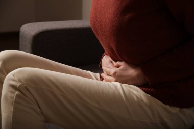 Mide ağrısı. Karın ağrısı ya da regl sancısı çeken bir kadın. Genç bir kadın dairede karın ağrısı çekiyor.. 