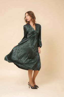 Stüdyo fotoğrafları. Güzel, ipek, saten bir elbise giymiş genç bir kadın model..