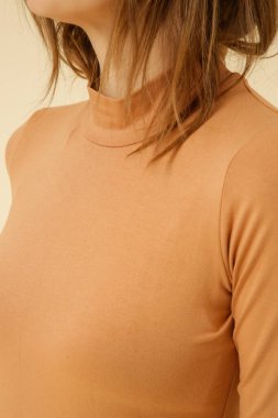 Organik pamuktan yapılmış bej balıkçı yaka giyen genç bir kadın modelin stüdyo fotoğrafçılığı. Rahat sürdürülebilir moda