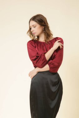 Bordo ipek bluz ve siyah Midi etek giyen bir kadın model. Şık ve şık bir kıyafet. Moda Stüdyosu çekimi.