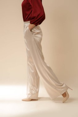 Stüdyo fotoğrafları, sade ipek saten elbiseler, bordo bluz ve bej geniş paça pantolon giyen genç kadın modeller..