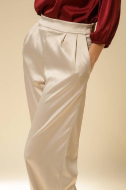 Stüdyo fotoğrafları, sade ipek saten elbiseler, bordo bluz ve bej geniş paça pantolon giyen genç kadın modeller..