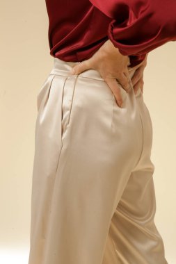 Stüdyo fotoğrafları, sade ipek saten elbiseler, bordo bluz ve bej geniş paça pantolon giyen genç kadın modeller..