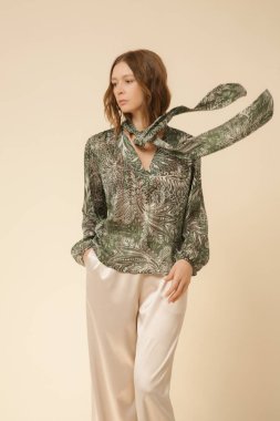 Stüdyo fotoğrafları, güzel sonbahar kıyafetleri giyen genç kadın modeller, sonbahar desenli yeşil boho bluz ve bej saten geniş paça pantolon.