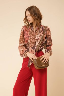 Stüdyo fotoğrafları, güzel sonbahar kıyafetleri, sonbahar desenli boho bluz ve kırmızı geniş paçalı pantolon giyen genç kadın modeller.