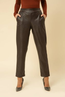 Stüdyo fotoğrafçılığı, yüksek topuklu kahverengi deri pantolon giyen genç bir manken.