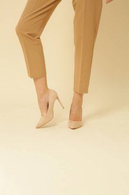 Stüdyoda çekilen fotoğraflarda, genç bir mankenin sigara kırıntısı bej pantolon giydiği görülüyor.