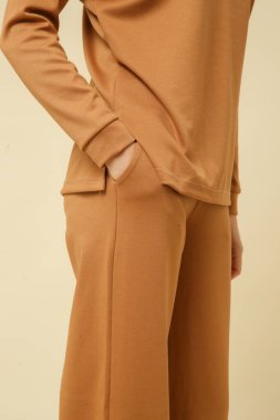 Loungewear pamuk giyen kadın model yumuşak ve rahat kıyafet, bej bluz ve pantolon. Klasik ve basit moda. Stüdyo çekimi. 