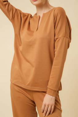 Loungewear pamuk giyen kadın model yumuşak ve rahat kıyafet, bej bluz ve pantolon. Klasik ve basit moda. Stüdyo çekimi. 