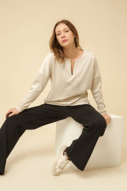 Çizgili siyah beyaz pantolon ve beyaz gömlek giyen bir manken.