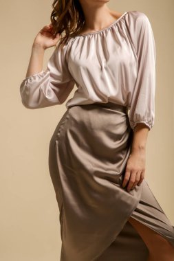 Bej ipek bluz ve Midi etek giyen bir kadın model. Şık ve şık bir kıyafet. Moda Stüdyosu çekimi.