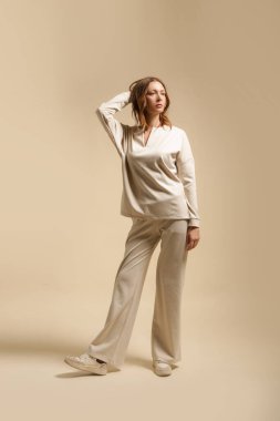 Loungewear pamuk giyen kadın model yumuşak ve rahat kıyafet, krem bluz ve pantolon. Klasik ve basit moda. Stüdyo çekimi. 
