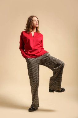 Houndstooth pantolon ve kırmızı gömlek giyen kadın model, stüdyo fotoğrafı.