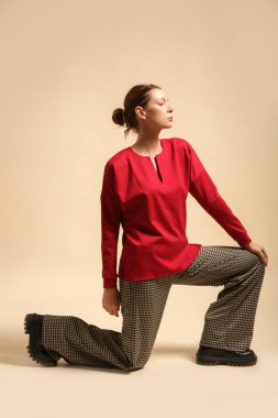 Houndstooth pantolon ve kırmızı gömlek giyen kadın model, stüdyo fotoğrafı.