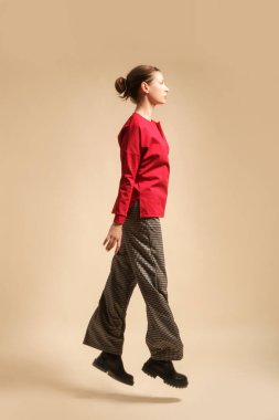 Houndstooth pantolon ve kırmızı gömlek giyen kadın model, stüdyo fotoğrafı.