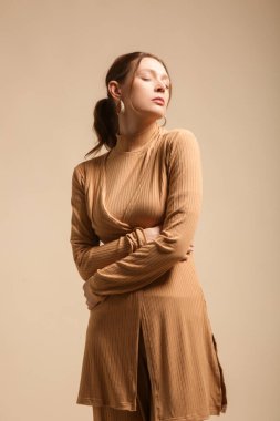 Rahat bej, rahat, şezlonglu bir takım elbise giyen bir kadın manken. Klasik ve basit moda. Stüdyo çekimi. 