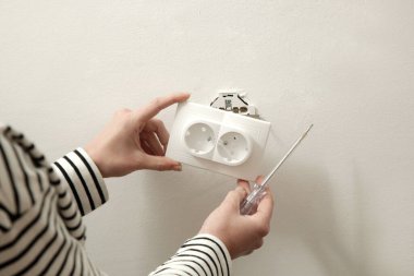 Elektrik prizi tamir ve montaj - ev geliştirme kavramları. Usta elektrikçi eve bir soket takıyor. DIY ev projesi.