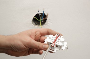 Elektrik prizi tamir ve montaj - ev geliştirme kavramları. Usta elektrikçi eve bir soket takıyor. DIY ev projesi.