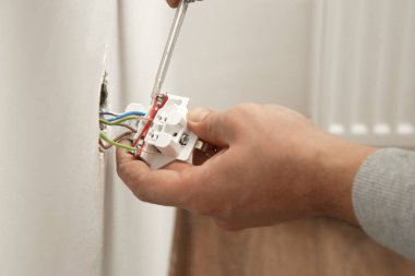 Elektrik prizi tamir ve montaj - ev geliştirme kavramları. Usta elektrikçi eve bir soket takıyor. DIY ev projesi.