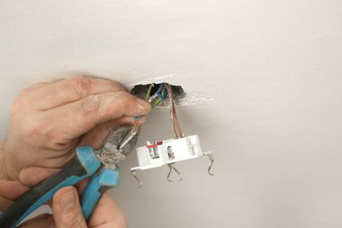 Elektrik prizi tamir ve montaj - ev geliştirme kavramları. Usta elektrikçi eve bir soket takıyor. DIY ev projesi.