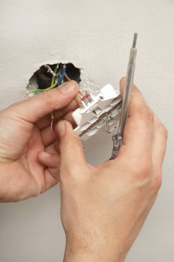 Elektrik prizi tamir ve montaj - ev geliştirme kavramları. Usta elektrikçi eve bir soket takıyor. DIY ev projesi.