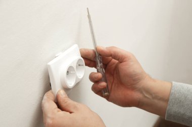 Elektrik prizi tamir ve montaj - ev geliştirme kavramları. Usta elektrikçi eve bir soket takıyor. DIY ev projesi.