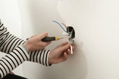 Elektrik prizi tamir ve montaj - ev geliştirme kavramları. Usta elektrikçi eve bir soket takıyor. DIY ev projesi.