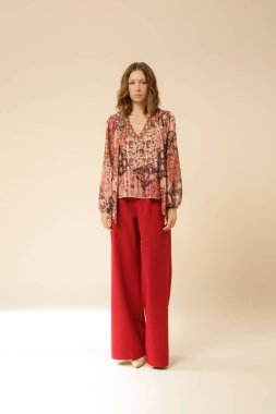 Stüdyo fotoğrafları, güzel sonbahar kıyafetleri, sonbahar desenli boho bluz ve kırmızı geniş paçalı pantolon giyen genç kadın modeller.