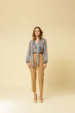 Stüdyo fotoğrafları, güzel sonbahar kıyafetleri, sonbahar mavi boho bluzu ve bej pantolon giyen genç kadın modeller.