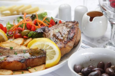 Patates ve yeşil salatayla servis edilen kaburga kemikli domuz pirzolası