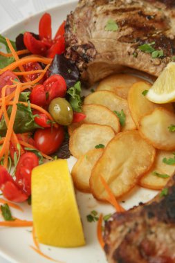 Patates ve yeşil salatayla servis edilen kaburga kemikli domuz pirzolası