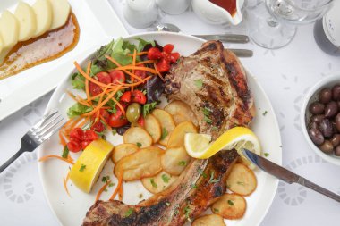 Patates ve yeşil salatayla servis edilen kaburga kemikli domuz pirzolası