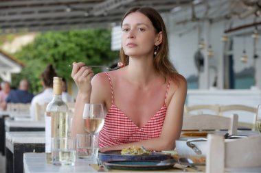 Young woman eating alone in the restaurant. Concept of solo dining in a casual restaurant. Eating out alone
