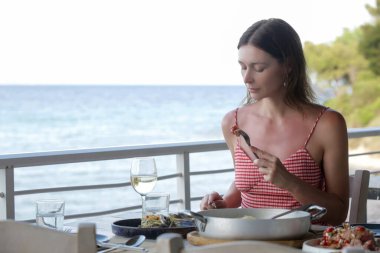 Young woman eating alone in the restaurant. Concept of solo dining in a casual restaurant. Eating out alone