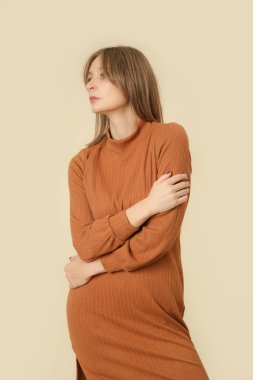 Stüdyo fotoğrafları, örgü bej bir elbise giymiş kadın model, sonbahar kış moda koleksiyonu.