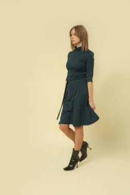 Stüdyoda çekilmiş yeşil ve siyah Midi elbiseli kadın modelin serisi. Sonbahar kış moda koleksiyonu..