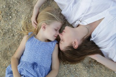 Annesiyle birlikte kumsalda yatan mutlu küçük kız. Mutlu huzurlu aile yaz tatili konsepti