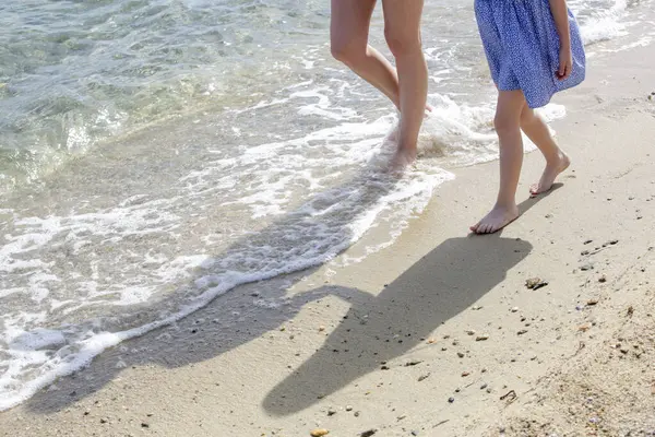 Kumsalda anne ve çocuğun çıplak ayakları..