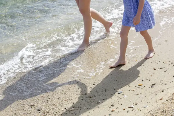 Kumsalda anne ve çocuğun çıplak ayakları..