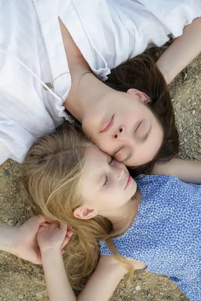 Annesiyle birlikte kumsalda yatan mutlu küçük kız. Mutlu huzurlu aile yaz tatili konsepti