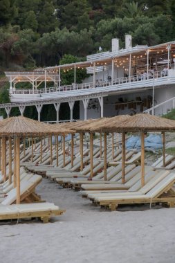 Boş plaj, saman şemsiyeler ve tahta güneşlikler.