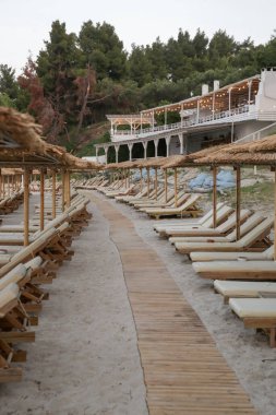 Boş plaj, saman şemsiyeler ve tahta güneşlikler.