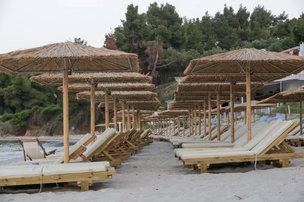 Boş plaj, saman şemsiyeler ve tahta güneşlikler.