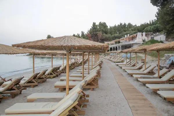 Boş plaj, saman şemsiyeler ve tahta güneşlikler.