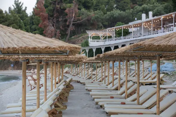 Boş plaj, saman şemsiyeler ve tahta güneşlikler.