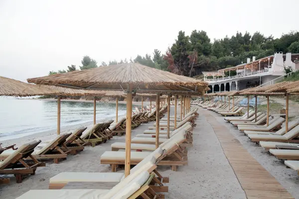 Boş plaj, saman şemsiyeler ve tahta güneşlikler.