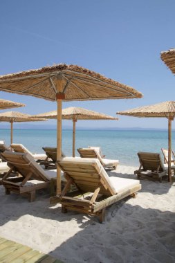 Boş plaj, saman şemsiyeler ve tahta güneşlikler.