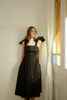 Omuz kemerlerinde fiyonkları olan zarif siyah Midi elbiseli kadın modellerin fotoğrafları.